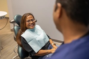 Patient smiling in dental chair while talking to dentist